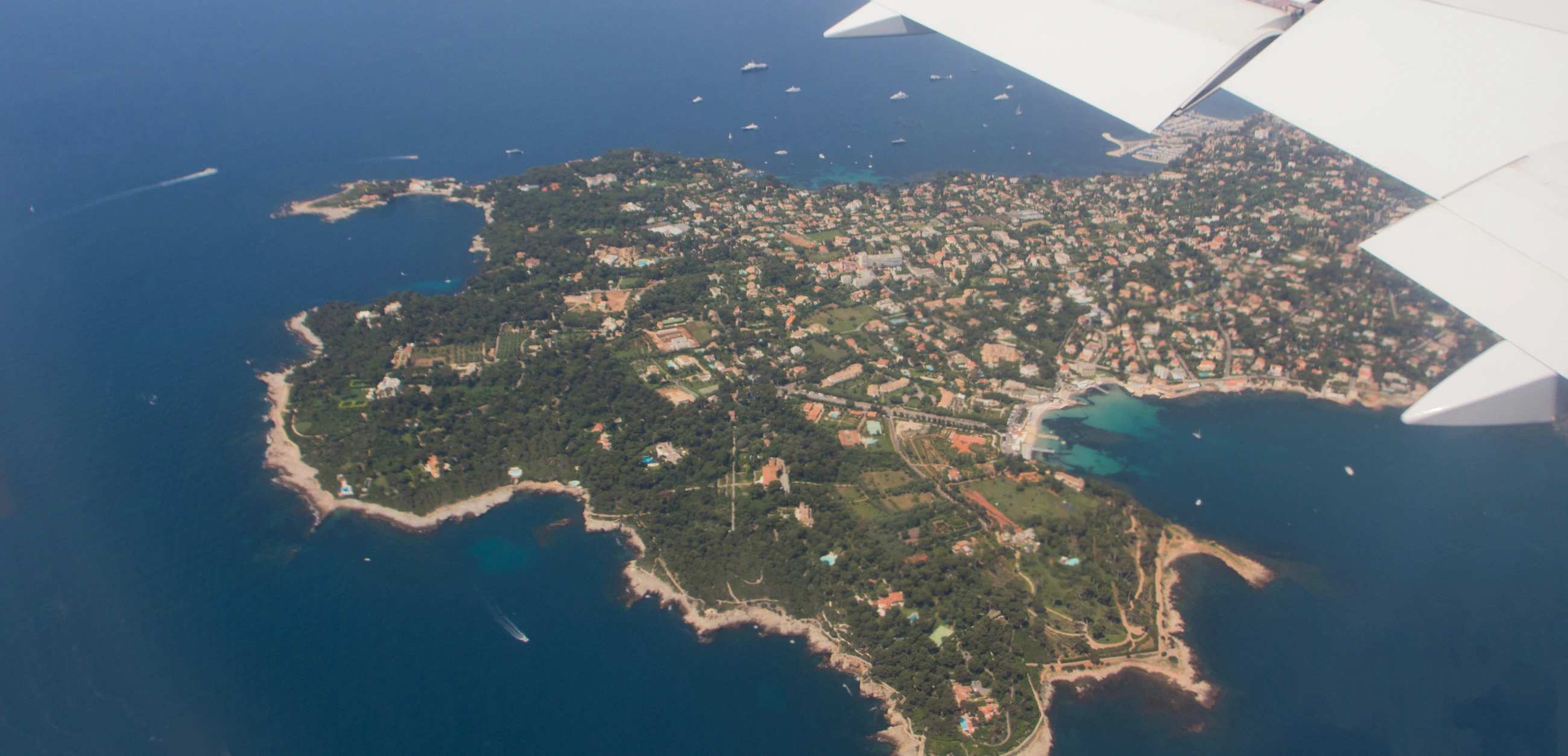 A coastal peninsula and blue sea seen from an airplane window