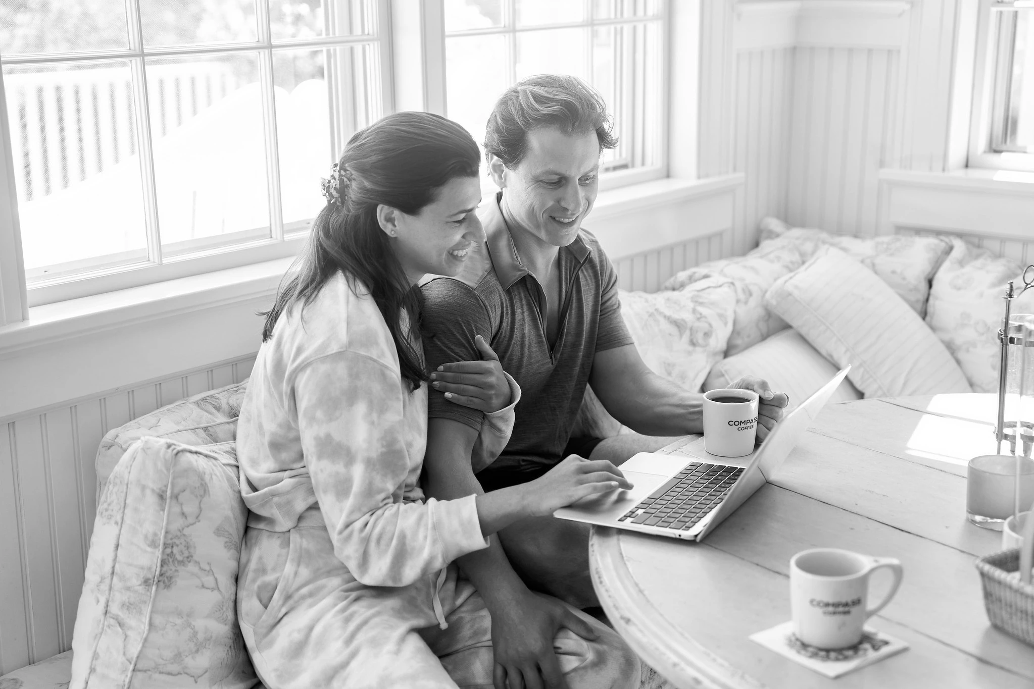 A couple sharing coffee and a laptop by the window in Nantucket